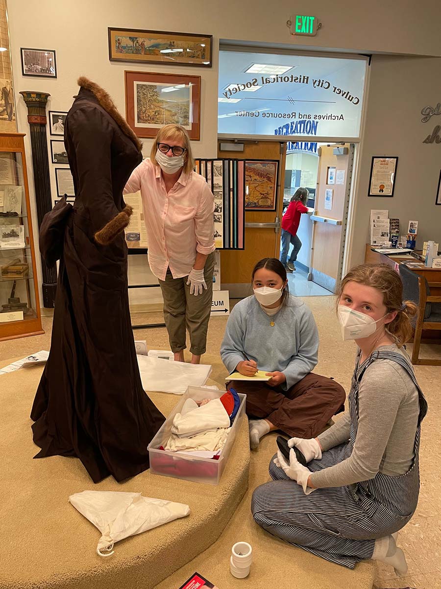 Dress was worn by Maria Schell in the 1958 production of “The Brothers Karamazov”. Working on the display is Valerie Meyer and interns Madisen Matsuura and Abigail Cregor.