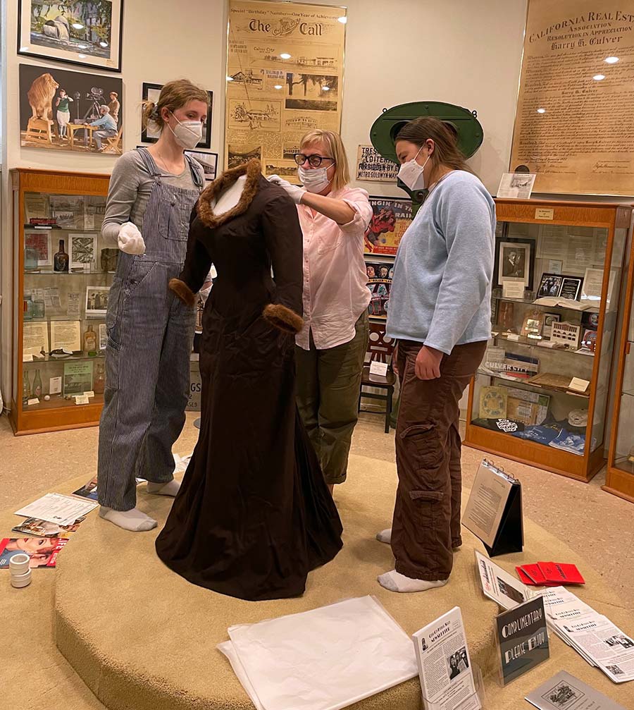 Dress worn by Maria Schell in “The Brothers Karamazov”. Working on the display is Valerie Meyer and interns Madisen Matsuura and Abigail Cregor.