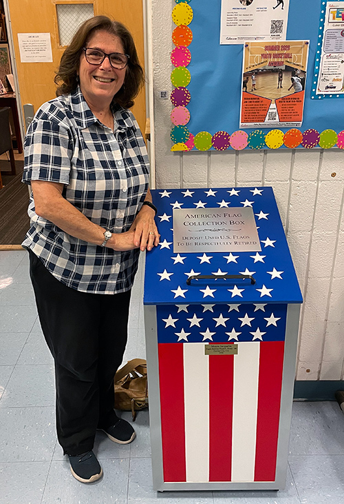 Beverly Peterson beside the Veterans Memorial Building collection box located next to the Parks and Recreation desk.