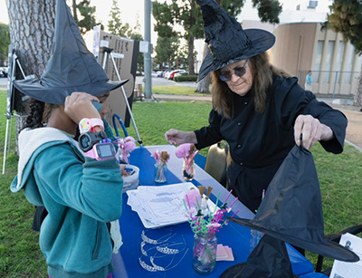 kid trying on a witch hat with Hope helping