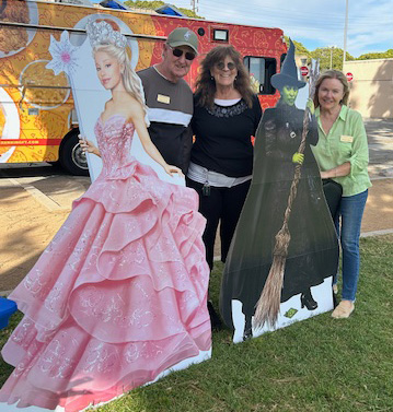 three people with Wicked character cut outs